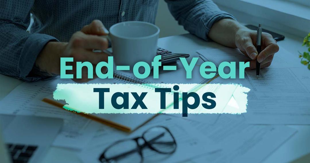 Person reviewing financial documents at a desk with a mug and glasses, overlaid with the text "end-of-year tax tips.