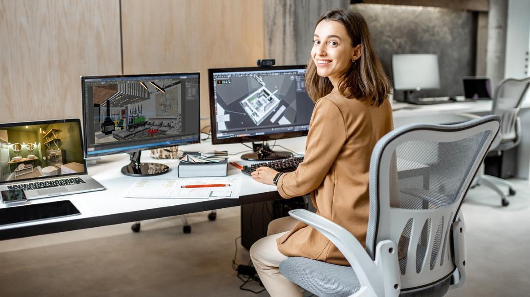 Young woman sitting at her desk smiling for a photo.
